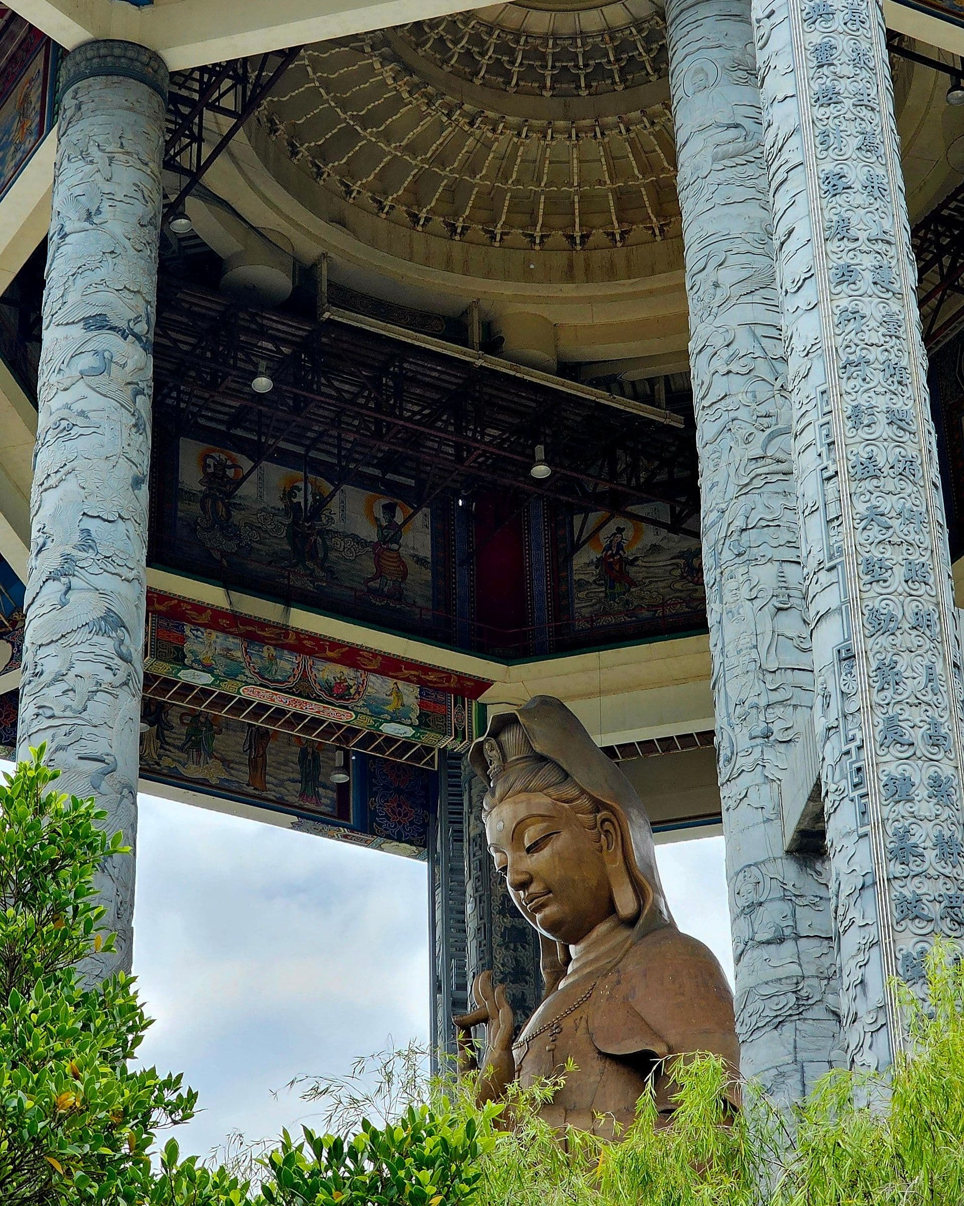 Rows of gilded Buddha statues and hanging lanterns inside a prayer hall at Kek Lok Si
